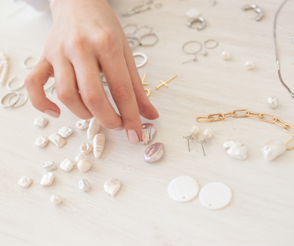 A hand touching beads for jewelry making.